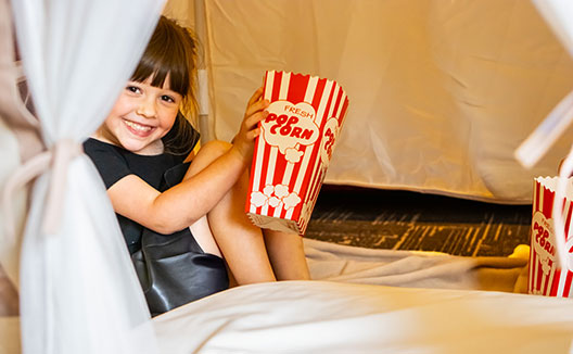 girl in play tent with popcorn bucket